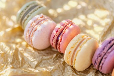 Altın bir kağıt ve ahşap masa üzerinde tatlı fransız renkli macaroons. Çay için lezzetli tatlılar.
