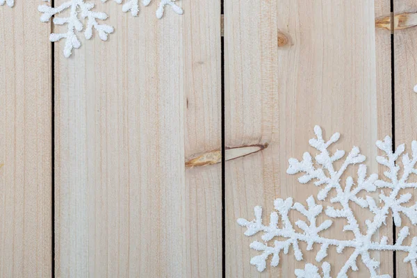 Білі штучні сніжинки на легкому дерев'яному столі. Різдвяний і новорічний прикраси фон і копіювання простору для тексту. крупним планом — стокове фото