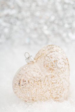 Karda cam kalp. Parlayan ışıklar ile ışıltılı bokeh bulanık beyaz arka plan. Noel dekorasyonu. Kopyalama alanı