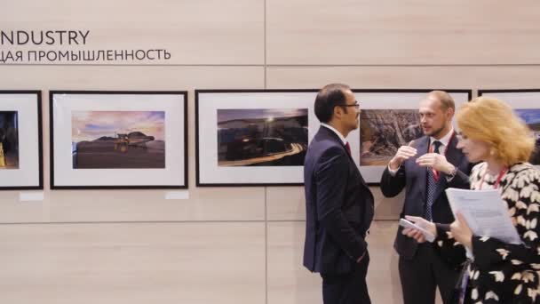 İki iş adamı tablolardan bahsediyor, insanlar sergiye gider Spief Saint Petersburg uluslararası ekonomik forum 2019 Expoforum — Stok video