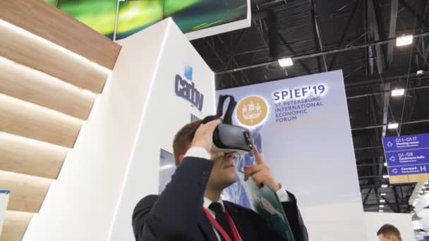 Biznesmen w garniturze próbuje okulary VR słuchawki na wystawie Spief Sankt Petersburg International Economic forum 2019 ExpoForum — Wideo stockowe