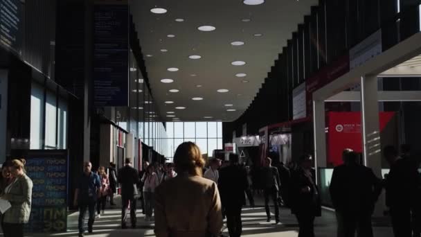 Zakelijke vrouw meisje lopen in de hal van de tentoonstelling in de schaduw en stralen van het zonlicht Spief Sint-Petersburg internationaal economisch forum 2019 Expoforum — Stockvideo