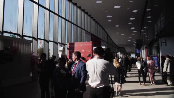 Οι επιχειρηματίες περπατούν γύρω από την αίθουσα επίδειξης στη σκιά και το ηλιακό φως Spief Αγία Πετρούπολη διεθνές οικονομικό φόρουμ 2019 έκεκς — Αρχείο Βίντεο
