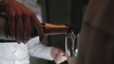 Beyaz gömlekli garson, elinde ki bir bardağa dökülür.