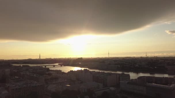 Belle vue aérienne du coucher du soleil sur le panorama de la ville de Saint-Pétersbourg, le remblai de la rivière Neva, les reflets de l'eau, les nuages, les ponts, les toits, les voitures de circulation sur la route entre les bâtiments — Video
