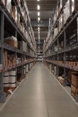 Tavana kadar rafları olan büyük bir deponun uzun koridoru.