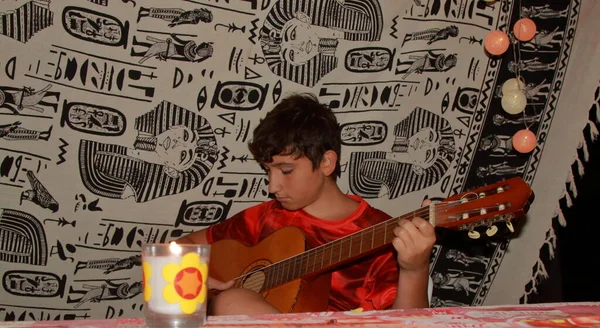 一个高加索男孩在海滩露营时弹奏吉它 — 图库照片