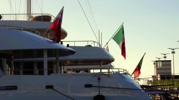 Itálie, léto 2020: Námořní vlajky Itálie a Kajmanských ostrovů se kolébají od zádi luxusních jachet — Stock video