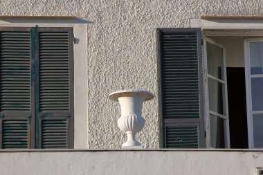 Deniz kenarındaki bir evin balkonunda duran beyaz vazo.