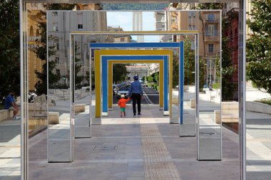 LaSpezia, İtalya - 2020 yazı: bir adam ve çocukları şehir parkında renkli bir koridorda yürüyorlar