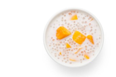 Beyaz arka planda mango ve hindistan cevizi sütü ile tatlı sago krem bir kase. Üstte görüntü.