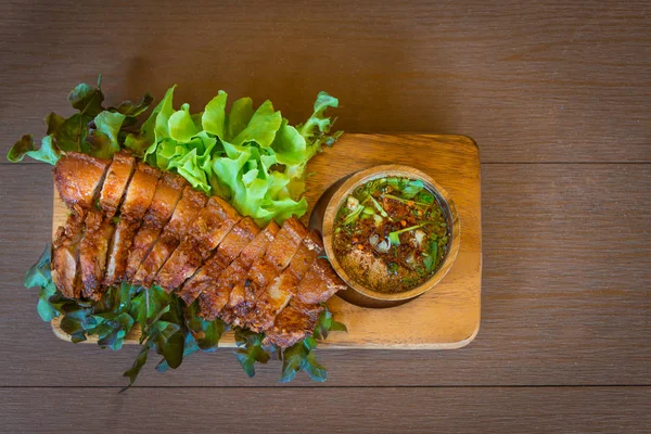 Crispy pork belly or deep fried crispy pork with hot and spicy sauce Thai style delicious food on wooden table
