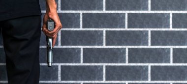 Soyguncu veya gangster, hırsız, vurgun adam elinde gri tuğla duvar suç kavramı ile ateş etmeye hazır silah tutan.