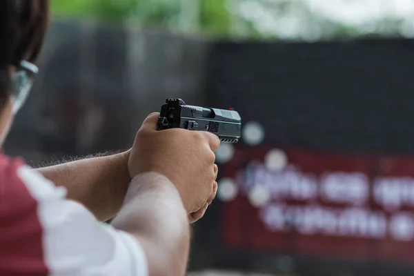 Man holding gun aiming pistol in shooting range