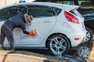 Oto yıkamada süngerle otomobili temizleyen adam işçi