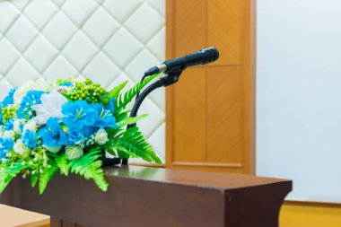 Güzel çiçeklerile konferans odasında masada Mikrofon