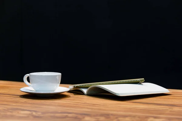 A cup of coffee and notebook on wooden table