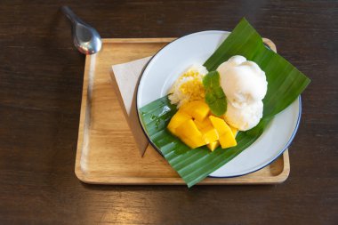 Ahşap masada muz yaprağı üzerinde mango ile dondurma hindistan cevizi sütü lezzetli Tay füzyon tatlı