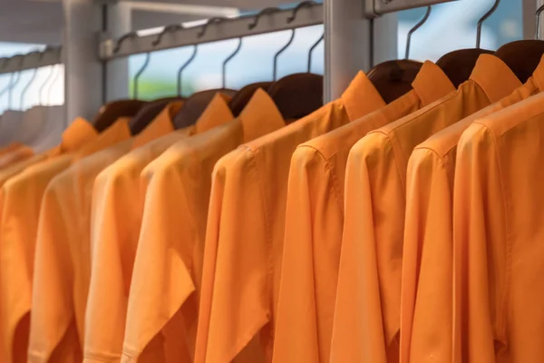 Men orange shirt hang in a wooden closet at modern home