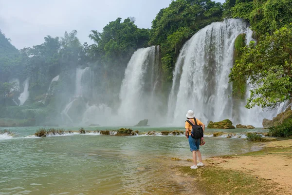Women are watching Ban Gioc or Detain waterfall flow down fluted is famous place travel destination the most popular one of the top 10 waterfalls in the world along Cao Bang, Vietnam and China border