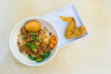 Pişmiş domuz pirinci ve yumurta ve tatlı kahverengi soslu kızarmış tavuk kanadı Singapur 'da ahşap masada lezzetli yemekler.