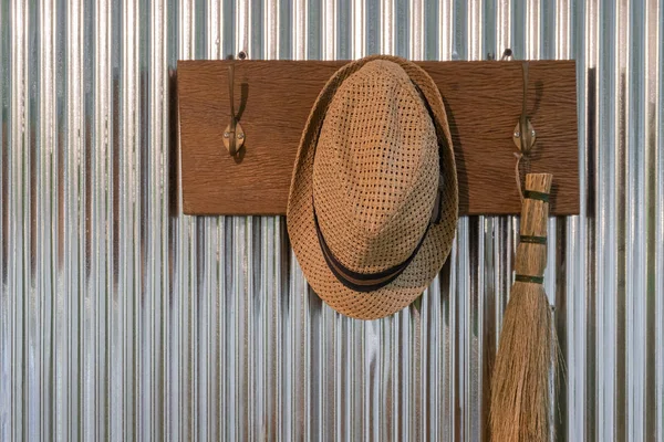 Vintage Straw hat on cloth hanger on the zinc wall interior decoration concept