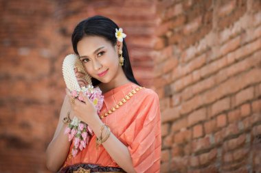 Tayland 'da Ayutthaya, Tayland' daki antik tapınakta Tayland kültürüne göre ellerinde güzel çelenklerle ve geleneksel Tayland elbisesi giymiş güzel Asyalı kadınlar.