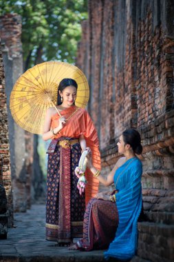Tayland 'da Ayutthaya, Tayland' daki antik tapınakta Tayland kültürüne göre ellerinde güzel çelenklerle ve geleneksel Tayland elbisesi giymiş güzel Asyalı kadınlar.