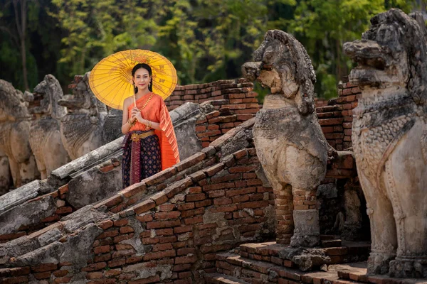 Asian women with umbrella, Pretty girl wearing in Thai traditional dress costume according Thai culture at the historical ancient temple Ayutthaya, Thailand