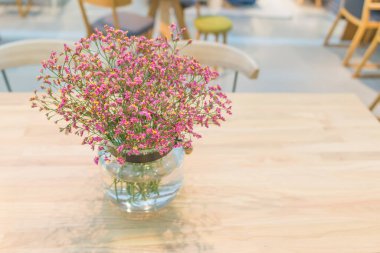 Ahşap masa iç mimarisi üzerine dekore edilmiş vazodaki güzel pembe çiçek bitkisi ofis binası veya ev ve yaşayan akitektür dekorasyonu çağdaş konsepti için.