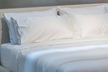 Ev ve canlı akitektür dekorasyonu çağdaş konforlu rahatlama konsepti için yatağın iç kısmında beyaz kumaş yastıklar.