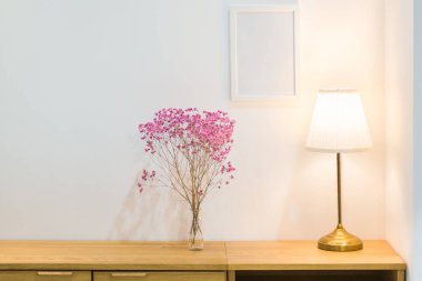 Vazodaki güzel pembe çiçek ayakta duran lamba ve ahşap dolabın içindeki beyaz çerçeveli fotoğraf ofis inşaatı veya ev ve canlı akitecture dekorasyonu çağdaş konsepti için.
