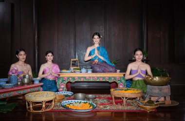 Geleneklere ve kültüre göre geleneksel Tayland kostümü giyen güzel bir Asyalı kadın grubu Tayland usulü Ayutthaya, Tayland usulü tapınmak için el ele tutuşur ve saygılarını sunarlar.