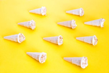 Trendy güneş ışığı Yaz deseni. Waffle bardaklarında fındıklı dondurma. Waffle konileri sarı bir arka plan üzerine serilmiş.