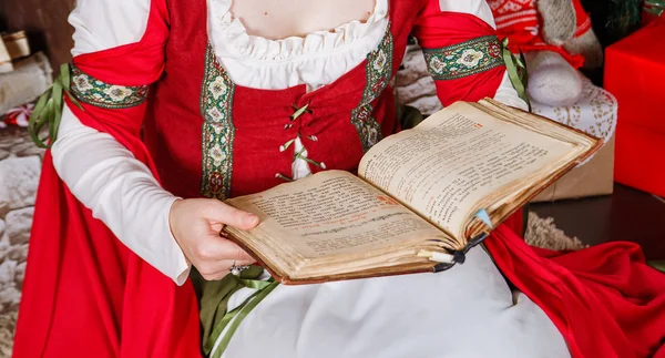 Mãos de uma menina em um vestido medieval segurando um livro antigo aberto. O conceito de um conto de fadas fantástico histórias mágicas . — Fotografia de Stock