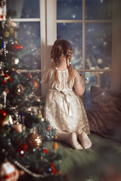 Bir çocuk Noel gecesi donmuş pencereden büyü bekliyor. Kartpostal konsepti, kitap kapağı.