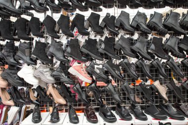 Çinli siyah kadın botları ve spor ayakkabıları pazarda sırayla asılı. Satış nitel kadın ayakkabısı değildir. Rusya, Abakan 23.09.2019.