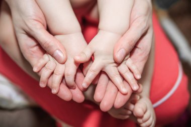 Bir anne küçük ellerini nazikçe tutar. Mutlu annelik kavramı, çocukların ve ebeveynlerinin bakımı ve sevgisi..