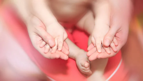 Een moeder houdt zachtjes haar kleine handjes vast. Het concept van gelukkig moederschap, zorg en liefde voor kinderen en hun ouders. — Stockfoto