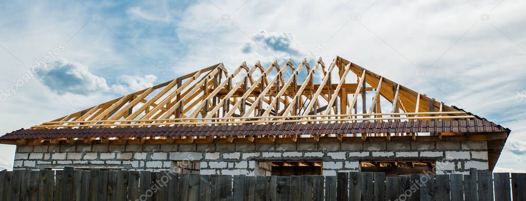 Installation of a wooden roof and Closing the roof with Onduvilla bituminous tiles. Woods elements and components of the construction of roof. Ceiling beams of natural eco-friendly materials.