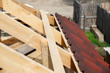 Ahşap bir çatı kurulumu ve Onduvilla bituminous fayanslarıyla çatının kapatılması. Çatı inşaatının ahşap elementleri ve parçaları. Doğal çevre dostu malzemelerin tavan kirişleri..