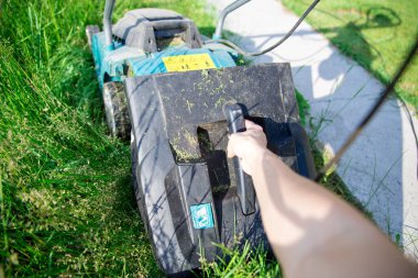 Makita elektrikli çim biçme makinesiyle çimlerin nasıl biçileceğine dair adım adım talimatlar. Doldurduktan sonra, toplanan otların olduğu kabı kaldırın. Abakan, Rusya-12 Haziran 2020