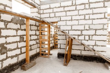 İnşaat halindeki bir evin inşaatı. Beyaz havalandırmalı beton bloklardan yapılmamış ev duvarları. Yönetim kurulları ve Avrupa paletlerinden toplanan işçilerin yapı iskelesi