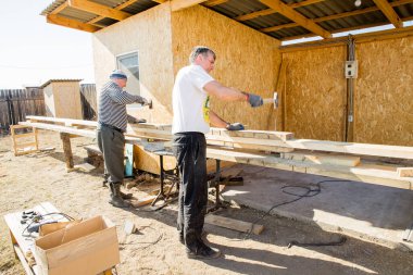 Ahşap tahtaları çatı inşaatı için hazırlayın. İnşaat marangozluğu. İşçiler çekiçle tahtaları birbirine vurur. Abakan, Rusya-6 Nisan 2020