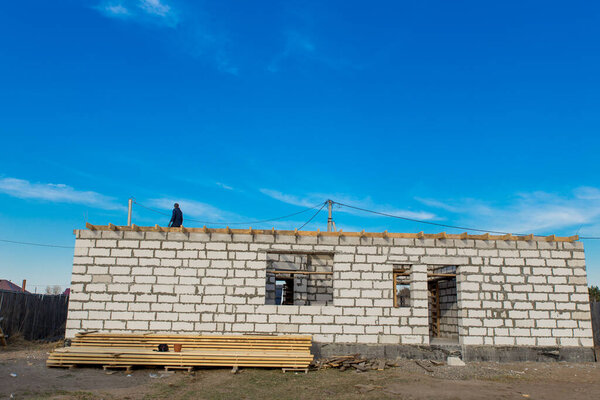 Строительная площадка строящегося дома. Недостроенные стены дома выполнены из белого автоклавного газобетонного типа блоков против голубого неба. Абакан, Россия-13 апреля 2020 года