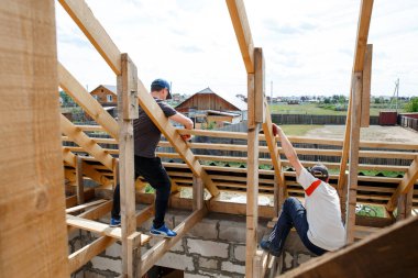 Çatı kirişlerinin işçiler tarafından döşenmesi. Geçmişe sünger çekmek için hazırlık. İnşaat ve tesis marangozluğu. Abakan, Rusya-8 Haziran 2020.