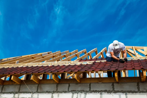 Ahşap bir çatı kurulumu ve Onduvilla bituminous fayanslarıyla çatının kapatılması. Çatı inşaatının ahşap elementleri ve parçaları. İnşaatçı ziftle çivilenmiş. Abakan, Rusya-8 Haziran 2020.