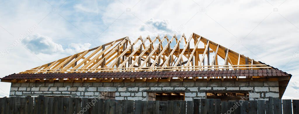 Installation of a wooden roof and Closing the roof with Onduvilla bituminous tiles. Woods elements and components of the construction of roof. Ceiling beams of natural eco-friendly materials
