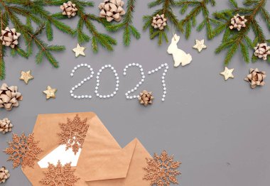 Üzerinde kozalaklı dallar ve Noel oyuncakları olan gri-mavi bir arkaplanda Noel mektubu. Kurdeleli, kar taneli, kozalaklı ve yıldızlı altın süslemeli Noel arkaplanı. Noel Baba 'ya Mektup