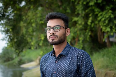 Genç ve yakışıklı bir Hintli Bengalli 'nin portresi. Prinsep Ghat' in önünde duruyor. Üzerinde mavi bir gömlek var. Hint yaşam tarzı ve moda